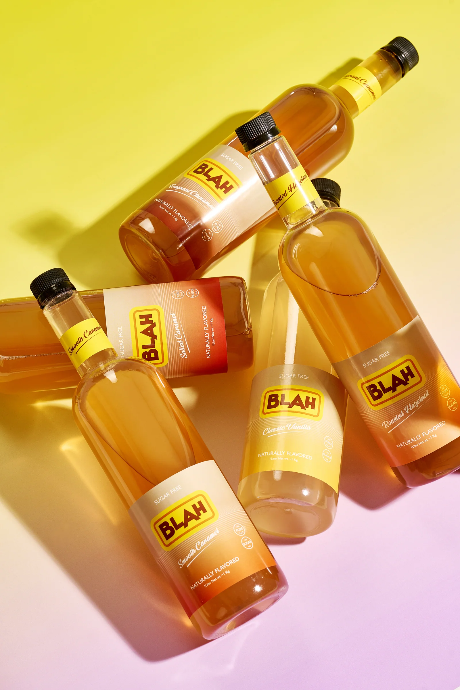 Five Blah sugar-free syrups piled on a yellow-lilac gradient